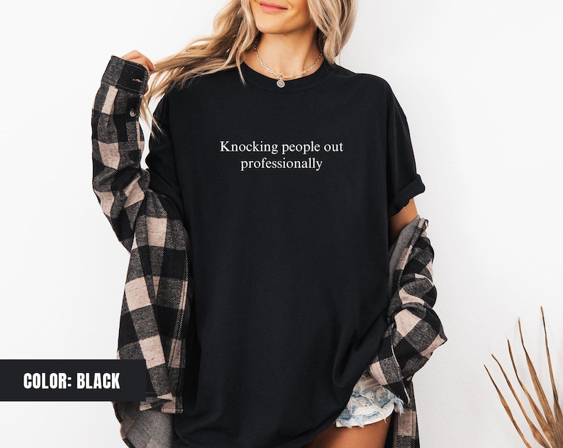 May include: Black t-shirt with the text "Knocking people out professionally" printed on the front.