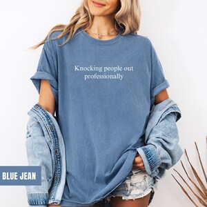 May include: A blue jean t-shirt with the text "Knocking people out professionally" printed on the front.