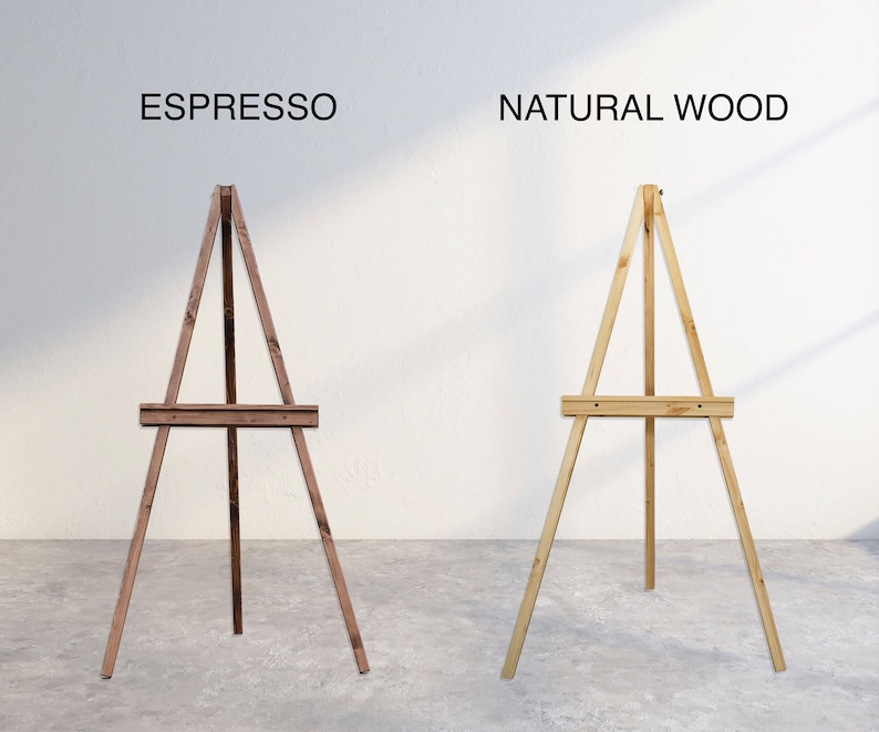 K&ouml;nnte beinhalten: Zwei Holzstaffeleien, eine in Espresso-Braun und eine in Naturholz. Beide Staffeleien haben ein schlichtes Design mit drei Beinen und einer horizontalen Stange zum Halten einer Leinwand oder eines Schilds.