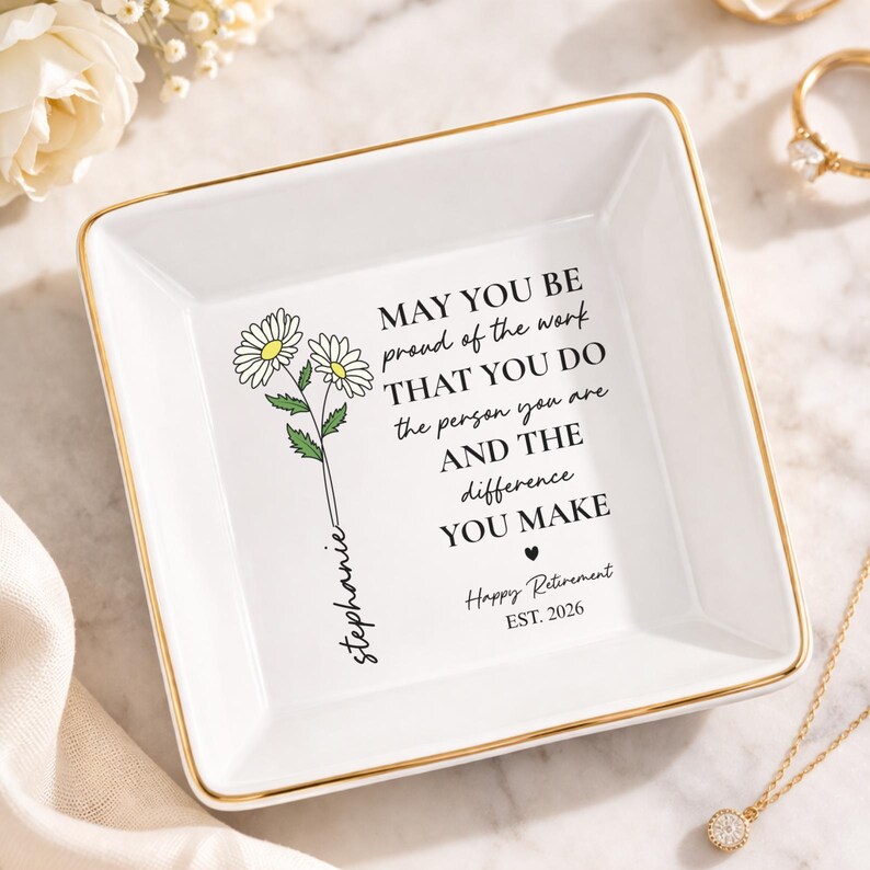 May include: A white ceramic square trinket dish with gold trim. The dish features a daisy floral design and the text "MAY YOU BE proud of the work THAT YOU DO...Happy Retirement EST. 2026" with the name "Stephanie".