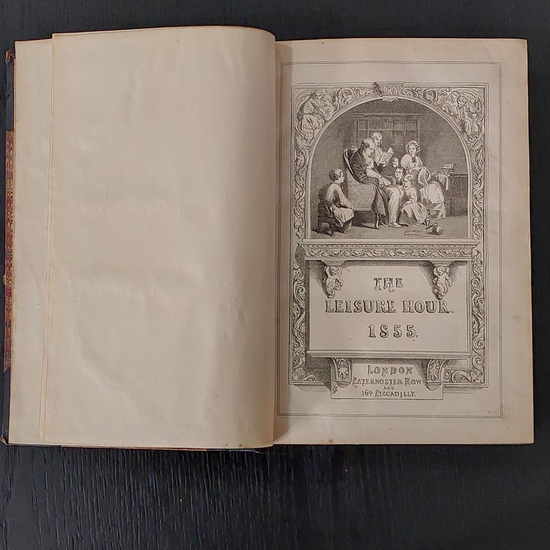 May include: Open antique book titled "The Leisure Hour" from 1855. The cover features an illustration of a family reading together. The book is open, revealing aged, cream-colored pages. The cover also includes the location "London" and the address "Paternoster Row, 164 Piccadilly."