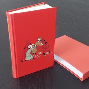 May include: A red hardback book with the title "The Scarlet Pimpernel" on the spine. The cover features an illustration of a group of people in period clothing.