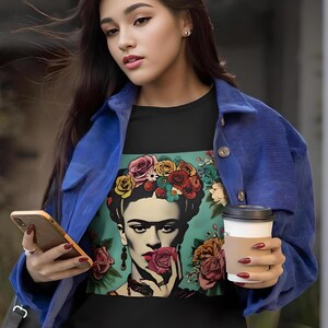 May include: A black t-shirt with a colorful image of Frida Kahlo wearing a flower crown and holding a rose. The image is surrounded by flowers.