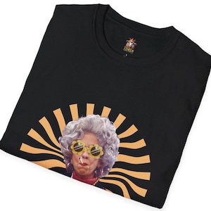 May include: Black t-shirt with a retro-style image of a woman wearing sunglasses and a cigarette. The image is surrounded by orange and yellow stripes.