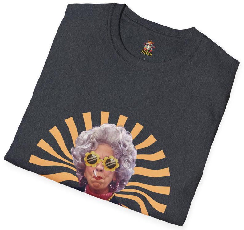 May include: A dark gray t-shirt with a graphic of a woman with gray hair wearing yellow sunglasses and a cigarette. The graphic is surrounded by orange and yellow sun rays.