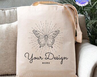 Op de afbeelding: Beige draagtas met lange handvatten, met een zwart vlinderontwerp met stralende lijnen. De tekst "Your Design HERE" staat onder de vlinder. De tas is gemaakt van een natuurlijk gekleurde stof.