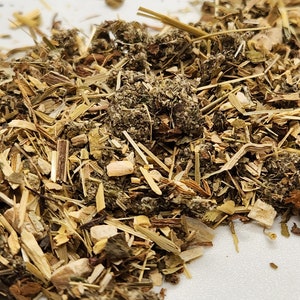 Puede incluir: Primer plano de un mont&oacute;n de hierbas secas y materia vegetal. La mezcla incluye varios tonos de verde, marr&oacute;n y beige, con tallos, hojas y peque&ntilde;os trozos visibles. La textura parece &aacute;spera y natural, lo que sugiere un producto herbal.