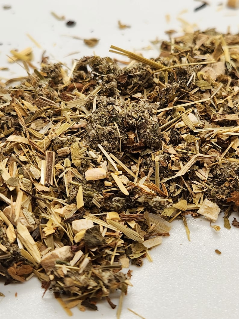 Puede incluir: Primer plano de un mont&oacute;n de hierbas secas y materia vegetal. La mezcla incluye varios tonos de verde, marr&oacute;n y beige, con tallos, hojas y peque&ntilde;os trozos visibles. La textura parece &aacute;spera y natural, lo que sugiere un producto herbal.