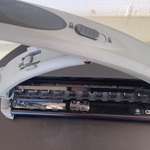 May include: A grey and black paper punch with a locking mechanism on the top handle. The device features a series of metal punch heads and a black base with the text arc printed in white on the right side of the front panel.