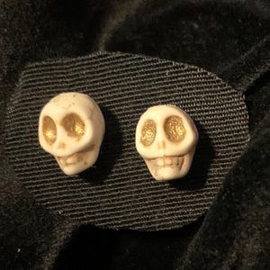 Skull Earrings studs with gold eyes and gold-colored stud and back. Wagnerite hand-painted skull jewelry.