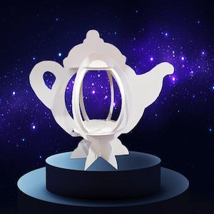 Puede incluir: Una escultura de papel blanco con forma de tetera con un interior abierto, sobre un fondo azul oscuro con efecto de estrellas. La tetera se encuentra sobre una plataforma de dos niveles, azul claro y azul oscuro.
