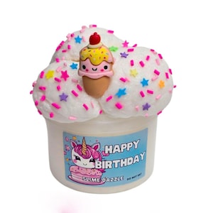May include: White slime with pink and white sprinkles in a clear container with a pink and white unicorn and the text "Happy Birthday Slime Dazzle Do Not Eat" on the label. The slime is shaped like a cupcake with a small ice cream cone charm on top.