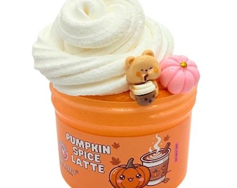May include: An orange container of slime topped with a swirl of white cream-colored slime. The container features a label with the text PUMPKIN SPICE LATTE, a cartoon pumpkin, and a coffee cup. A small bear charm and a pink pumpkin charm are included.