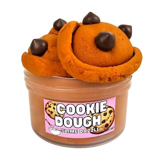 Może przedstawiać: Przezroczysty plastikowy pojemnik wypełniony brązowym slime'em o smaku ciasta na ciasteczka. Slime ma kształt ciasteczka z kawałkami czekolady. Pojemnik ma różową etykietę z napisem "Cookie Dough Slime Dazzle" i "Nie jeść".