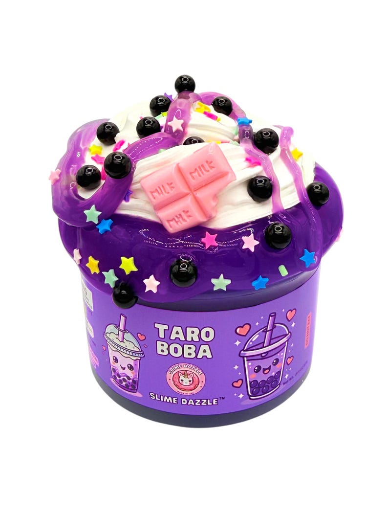 May include: A purple slime container labeled Taro Boba Slime Dazzle, topped with white cream, black boba beads, colorful star sprinkles, and a pink chocolate bar charm. The label features illustrations of two boba tea cups with faces.