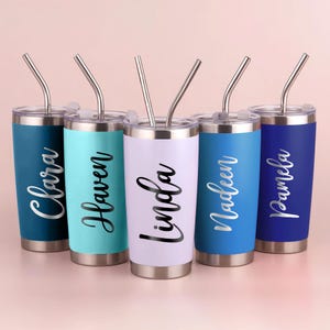 May include: Five personalized tumblers in shades of blue, teal, and lavender, each with a silver straw. The names "Clara", "Haven", "Linda", "Nadeen", and "Pamela" are printed in a cursive font on each tumbler.