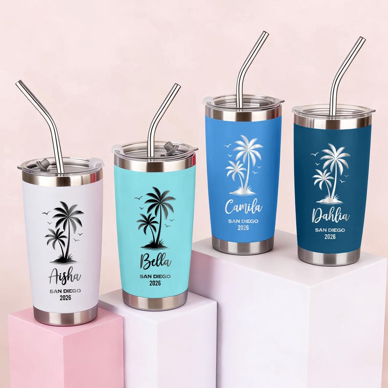 May include: Four stainless steel insulated tumblers with silver straws. Each tumbler is a different color: white, light blue, blue, and navy. Each tumbler has a black palm tree design and a name with "San Diego 2026" printed below.