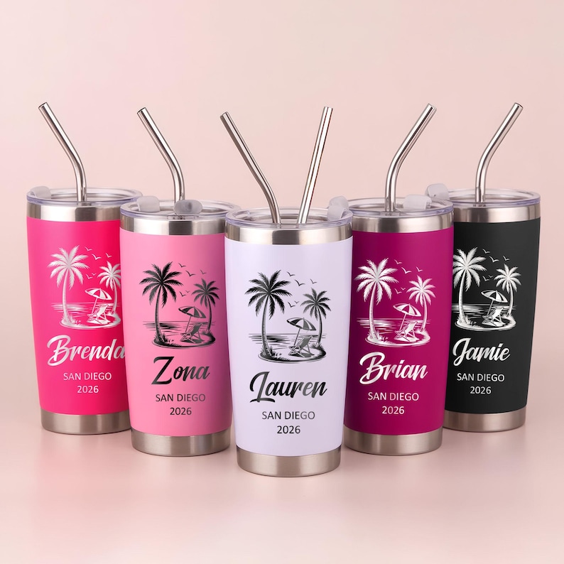 May include: Five stainless steel travel tumblers with silver straws. Each tumbler has a different color: pink, light pink, white, dark pink, and black. Each features a beach scene with palm trees and the name and year "San Diego 2026".