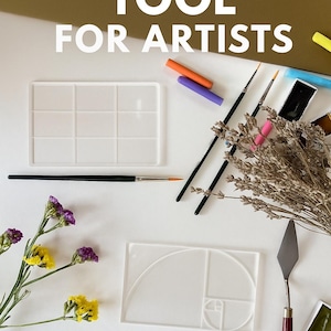 Puede incluir: Una colección de materiales de arte, que incluye pinceles, una paleta y una herramienta de proporción áurea, dispuestos sobre una superficie blanca. El texto "GOLDEN RATIO TOOL FOR ARTISTS" está en la parte superior. Flores secas y pasteles coloridos añaden interés visual.