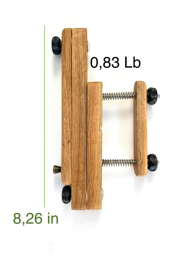 Wooden Mahlstick , light brown, 8.26 inches tall, 0.83 pounds.  Features two sets of parallel wooden blocks joined by a spring-loaded metal screw mechanism.  Black plastic knobs on each end.  A small metal pin is visible on the lower left side.  .