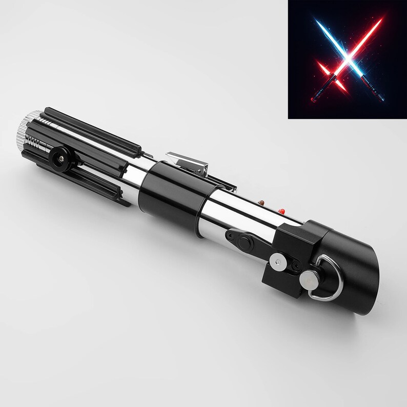 Puede incluir: Un sable de luz de r&eacute;plica con un mango negro y plateado. El mango tiene un dise&ntilde;o cil&iacute;ndrico con botones y un anillo en la base. Una imagen de sables de luz azules y rojos cruzados est&aacute; en la esquina superior derecha.