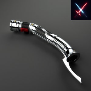 Puede incluir: Un sable de luz plateado con un mango negro y plateado. El sable de luz tiene una hoja roja y azul en el fondo.