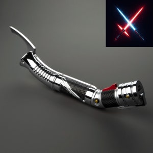 Puede incluir: Un sable de luz plateado con un mango negro y detalles rojos. El sable de luz es curvo y tiene un dise&ntilde;o detallado.