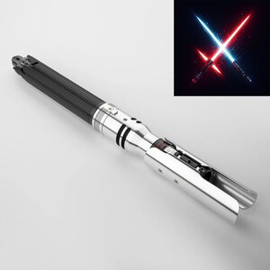 Puede incluir: Un sable de luz plateado y negro con un mango negro texturizado y un soporte de hoja plateado. El soporte de la hoja est&aacute; abierto, revelando los componentes internos del sable de luz.