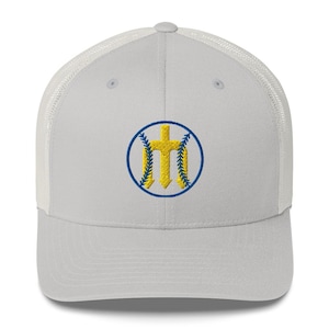 Puede incluir: Gorra de béisbol gris claro con la parte trasera de malla blanca. La gorra presenta un emblema circular con un diseño de tridente y cruz amarillo, delineado en azul. El sombrero es de estilo camionero.