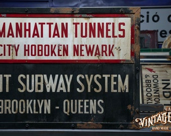 May include: A vintage, rusty metal sign advertising the Independent Subway System in New York City. The sign features the text "& Manhattan Tunnels", "Ey City Hoboken Newark", "DENT SUBWAY SYSTEM", and "-BROOKLYN - QUEENS".