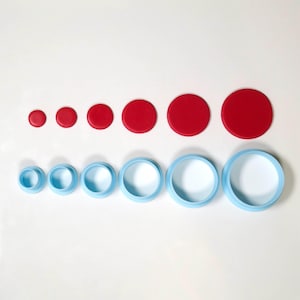May include: A set of red circular shapes and light blue ring-shaped objects of varying sizes. The objects are arranged in two rows, with the red circles above the blue rings. The sizes increase from left to right.