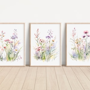 May include: Three framed watercolor paintings of wildflowers in shades of pink, purple, and green. The paintings are set against a white background and are framed in natural wood.