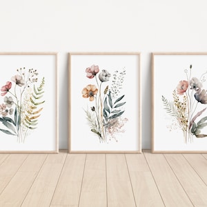 May include: Set of three watercolor prints featuring floral bouquets with pink, orange, and gray flowers, green leaves, and brown stems. The prints are framed in natural wood frames.