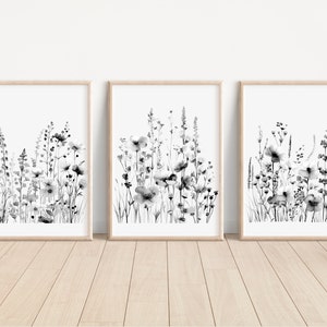 May include: Set of three black and white framed prints featuring a watercolor style illustration of a field of wildflowers.