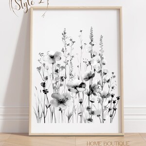 May include: Black and white watercolor painting of a field of wildflowers. The painting is framed in a light wood frame and is hanging on a white wall.