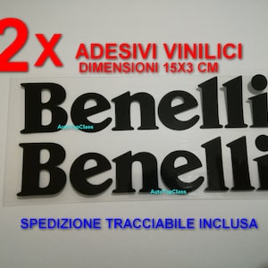 Può includere: Due adesivi in vinile nero con la scritta "Benelli" in lettere bianche. Gli adesivi misurano 15 cm per 3 cm. Il testo "2x Adesivi Vinilici Dimensioni 15x3 cm" è in lettere rosse. Il testo "Spedizione Tracciabile Inclusa" è in lettere blu.