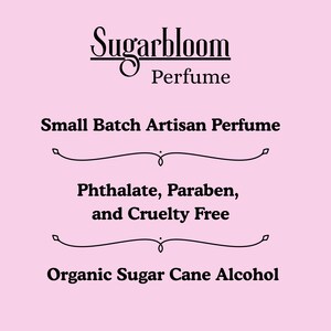 May include: A pink background with the text "Sugarbloom Perfume" in a decorative font. Below, it reads "Small Batch Artisan Perfume," followed by "Phthalate, Paraben, and Cruelty Free," and "Organic Sugar Cane Alcohol."