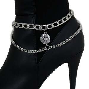 May include: A pair of black high-heeled boots with two silver chains and a silver charm dangling from the top chain.