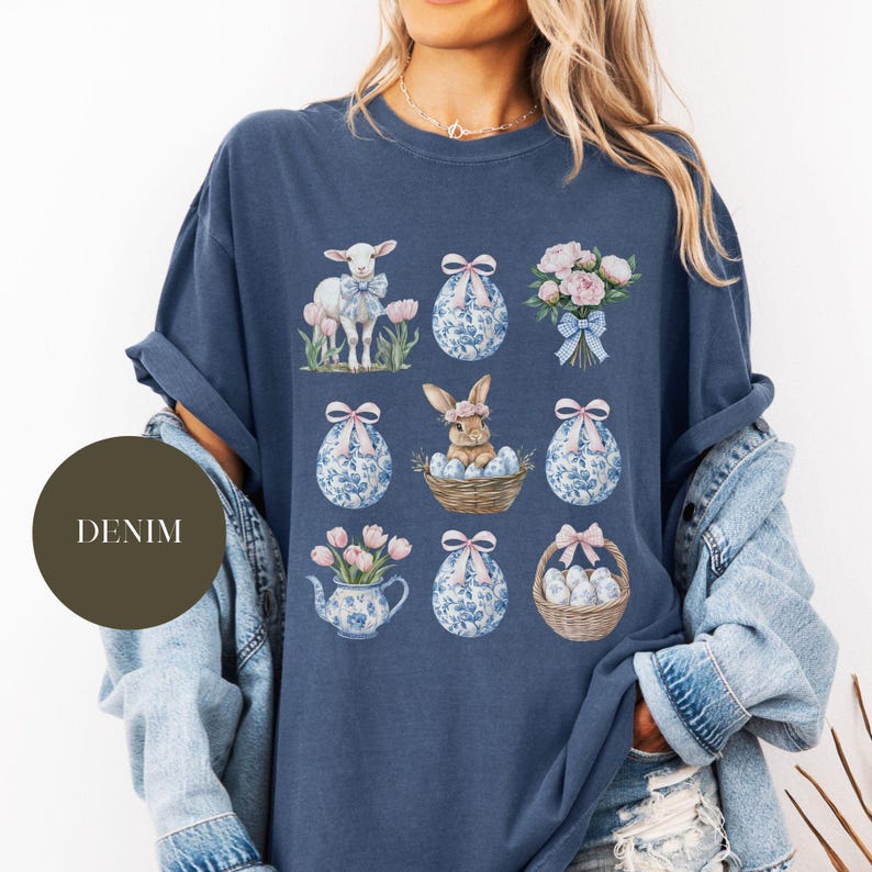 May include: A navy blue t-shirt with a graphic design featuring a variety of Easter-themed illustrations, including a lamb, a bunny, eggs, and flowers.