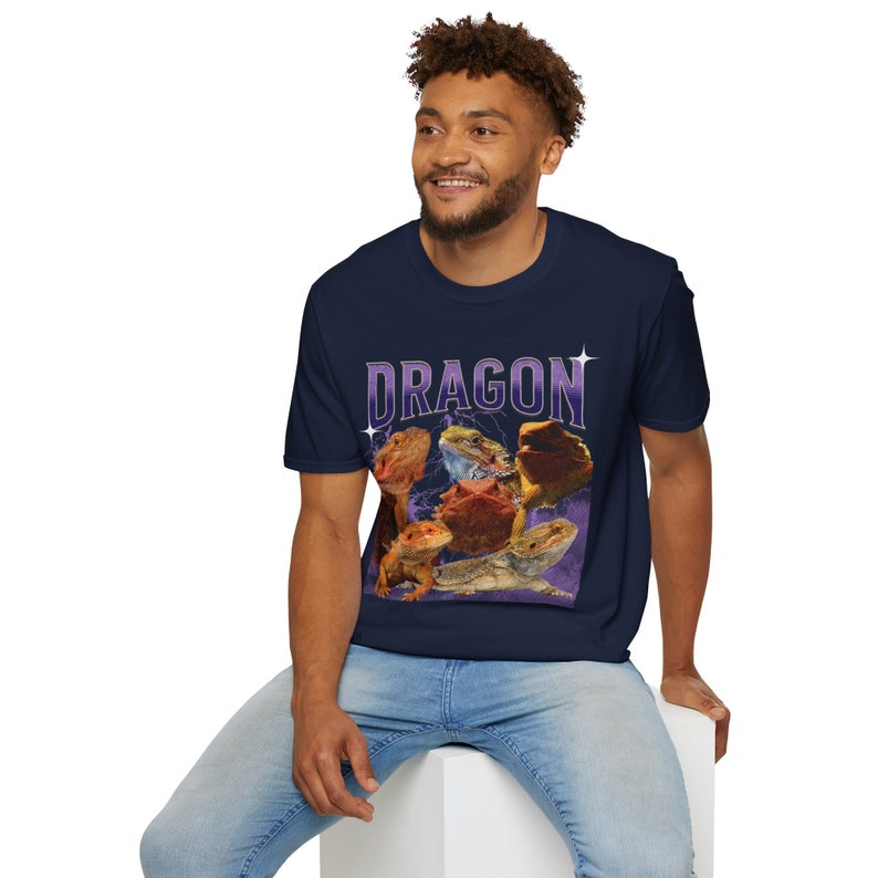 Puede incluir: Una camiseta azul marino con un gr&aacute;fico de varios dragones barbudos sobre un fondo morado. El texto "DRAGON" est&aacute; impreso en blanco con un contorno morado.