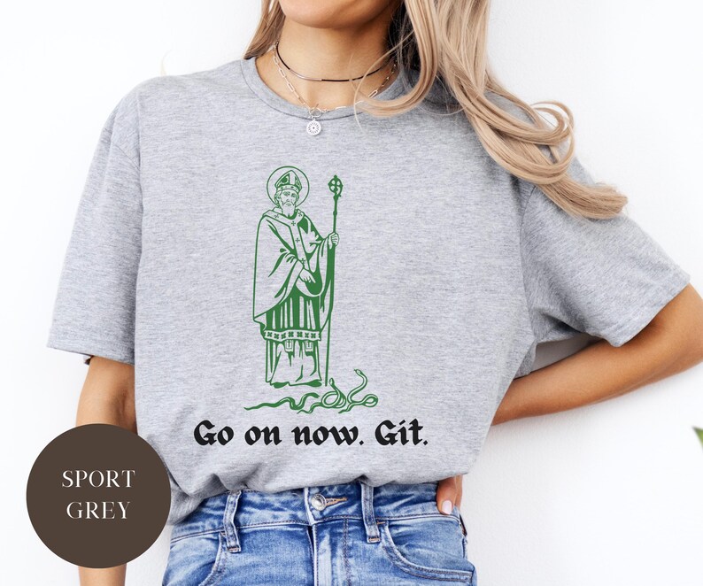 May include: A gray t-shirt with a green illustration of a man holding a staff. The text "Go on now. Git." is printed on the shirt.