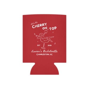 May include: Red drink koozie with white text and a graphic of a person on a cocktail glass. The text reads "She's the Cherry on Top" and "Lauren's Bachelorette Charleston, SC".