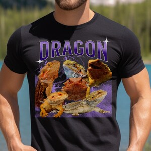 Puede incluir: Una camiseta negra con un gr&aacute;fico morado de cinco dragones barbudos. El gr&aacute;fico dice "DRAGON" en letras moradas grandes.
