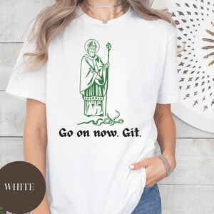 May include: White t-shirt with a green illustration of a man with a beard and a halo, holding a staff. The text "Go on now. Git." is printed below the illustration.
