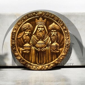 May include: A round, gold-colored wooden plaque with a raised image of the three wise men. The men are wearing robes and crowns, and they are holding gifts. The plaque is decorated with a floral design.