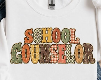 Könnte beinhalten: Ein weißes Langarm-Sweatshirt mit dem Schriftzug SCHOOL COUNSELOR in einer großen Retro-Schriftart. Jeder Buchstabe ist mit verschiedenen Mustern gefüllt, darunter Karos, Blumen und Vichy-Muster in gedeckten Orange-, Grün- und Brauntönen.