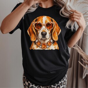 May include: A black short-sleeved t-shirt featuring a graphic print of a brown and white beagle dog wearing orange-tinted cat-eye glasses and a large, ornate necklace made of faceted orange and clear gemstones set in a metallic frame.