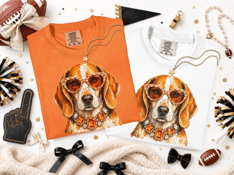 May include: Two Comfort Colors t-shirts, one orange and one white, each featuring a graphic print of a beagle dog wearing amber-colored sunglasses and a matching jeweled necklace. The shirts have a crew neckline and a tag printed on the inner collar.