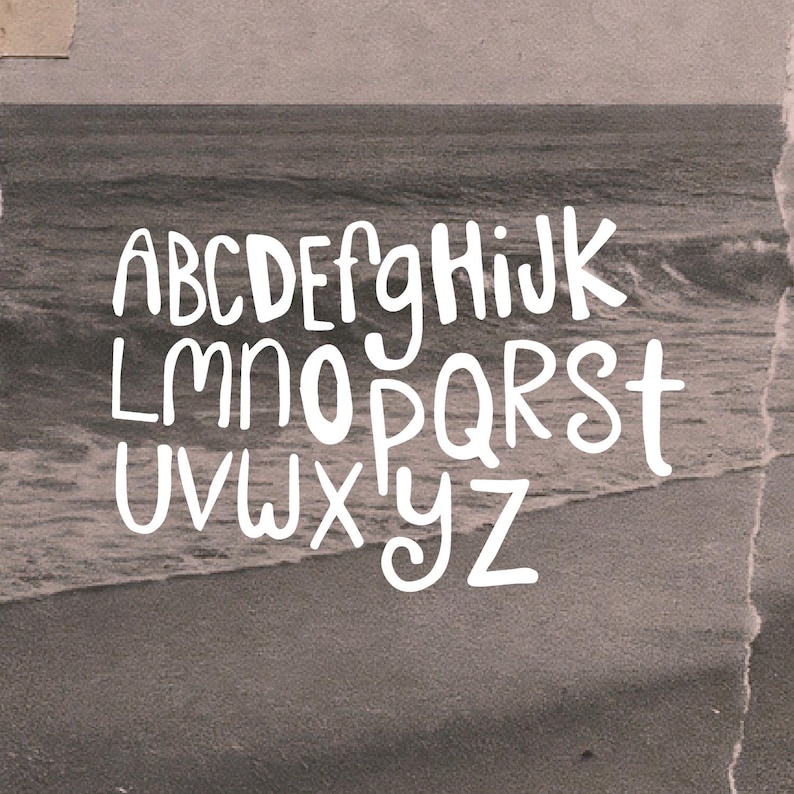 May include: White, handwritten-style alphabet letters A through Z are displayed against a sepia-toned background of a beach scene. The letters have a playful, rounded design, and the background has a torn paper effect.