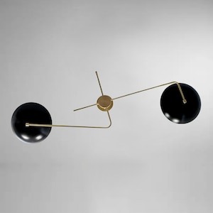 May include: A modern ceiling light fixture with two black spherical shades and gold metal arms.